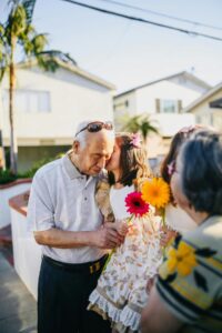 Grandfather inspired by child whispering in ear while holding flowers